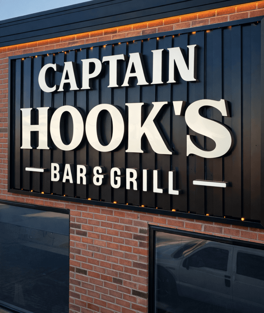 Captain Hook's Bar & Grill backlit dimensional letter sign on a brick and metal panel storefront