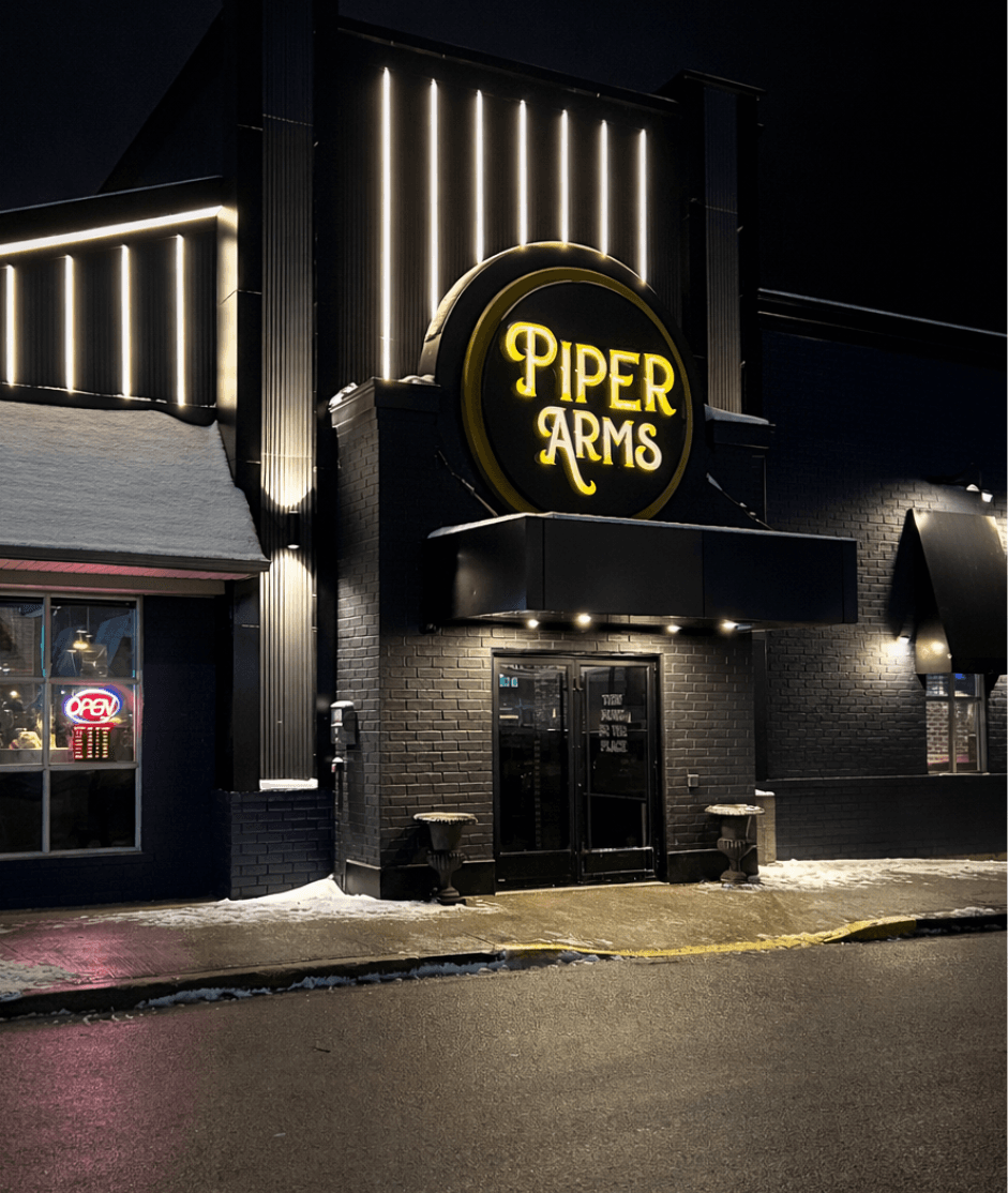 Piper Arms circular illuminated sign detail at night