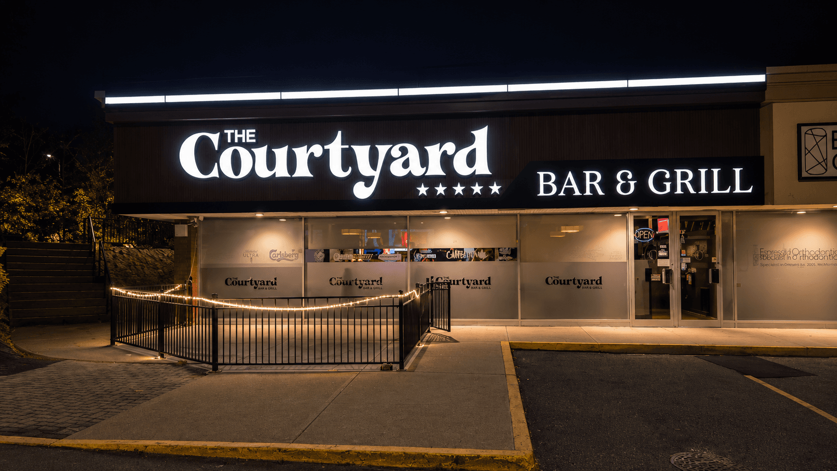 The Courtyard Bar & Grill illuminated wordmark sign and storefront at night